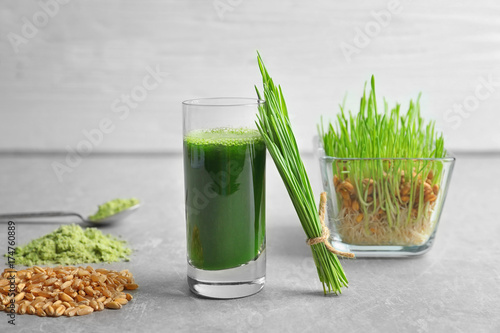 Wheat grass shot and grain on grey table
