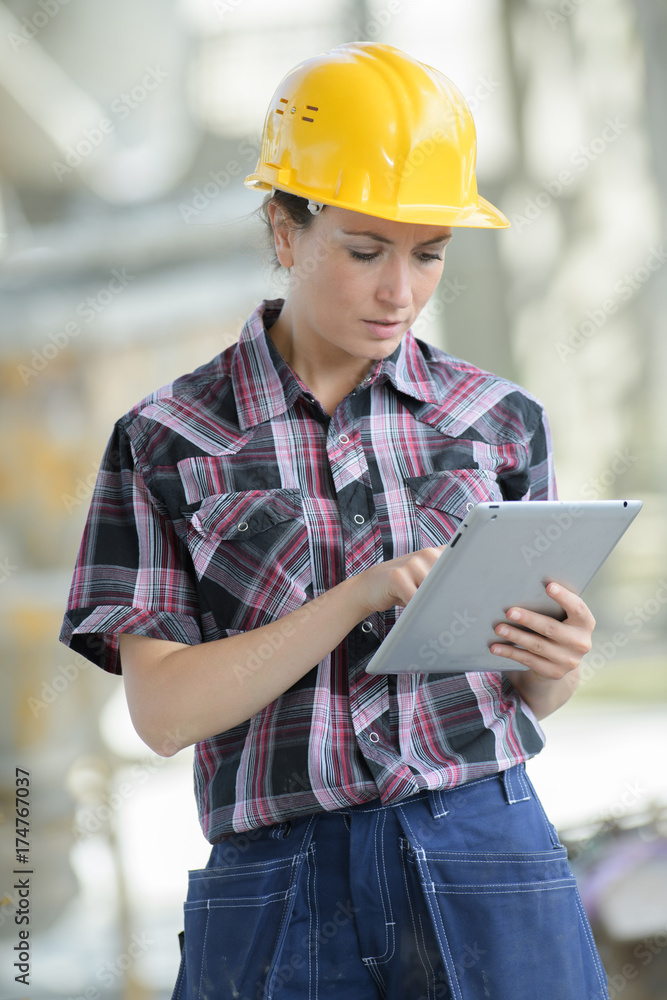 Fototapeta premium female contractor at a work site using an ipadtablet