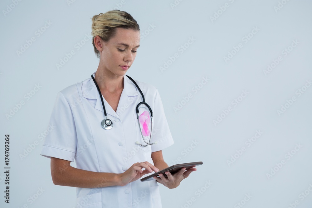 Female doctor with Breast Cancer Awareness ribbon using tablet Female doctor with Breast Cancer Awareness ribbon using tablet