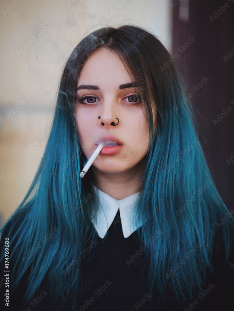 Emo girl smoking cigarette. Young student or pupil with blue