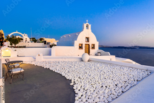 Oia town, Santorini island, Greece at sunset. Traditional and famous white churches  over the Caldera, Aegean sea. photo