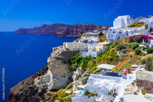 Oia, Santorini island, Greece. Traditional and famous white houses and churches with blue domes over the Caldera, Aegean sea.