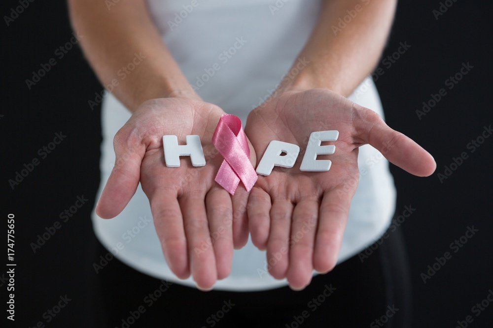 Mid section of woman holding pink ribbon with hope text Mid section of woman holding pink ribbon with hope text