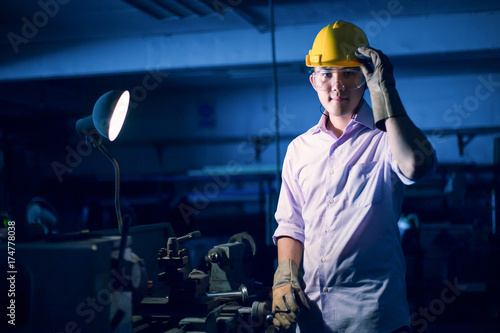 Portrait of young adult experienced industrial asian worker over industry machinery production line manufacturing workshop