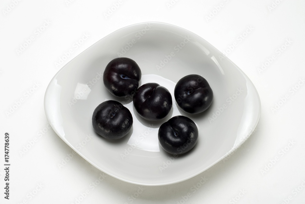 Black Amber Pflaumen (Prunus domestica) in a white bowl Black Amber Pflaumen (Prunus domestica) in a white bowl