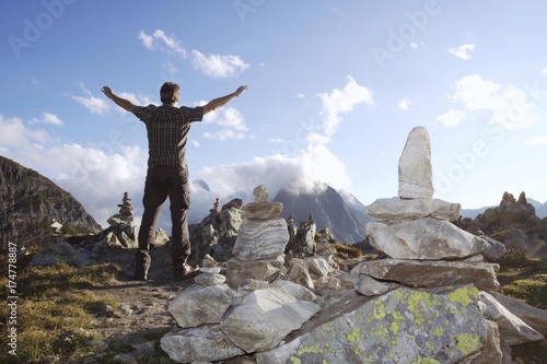 A hiker enjoys the freedom with view of the Bernese Alps on Nufenenpass, 2478m, behind the cloudy Mt. Faulhorn, 2865m, Canton Valais, Switzerland, Europe