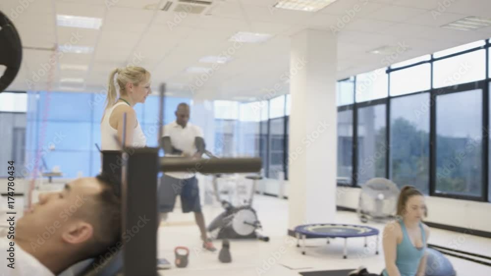 Personal trainer watching over clients, working out in modern gym Personal trainer watching over clients, working out in modern gym