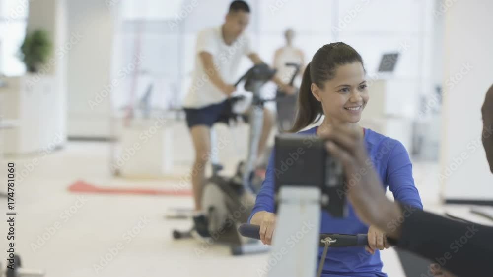 Young group working out in the gym with fitness instructor supervising Young group working out in the gym with fitness instructor supervising