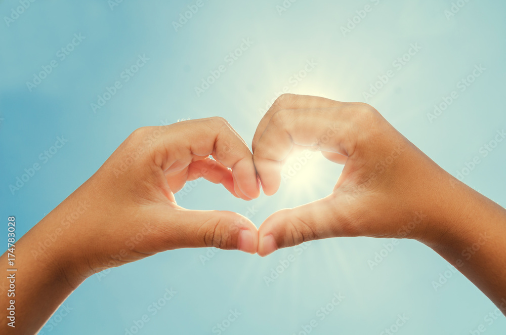 woman forming heart shaped hands with sun and blue sky background woman forming heart shaped hands with sun and blue sky background
