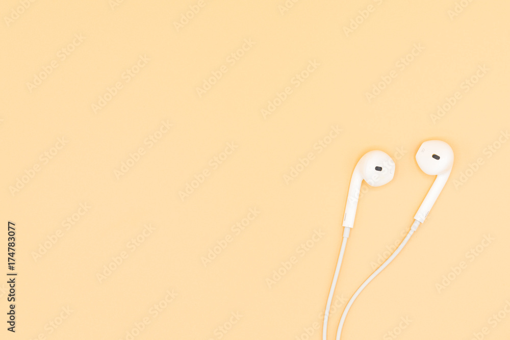 Top view of White Earphones on Orange background. Copy space. Music is my life concept Top view of White Earphones on Orange background. Copy space. Music is my life concept