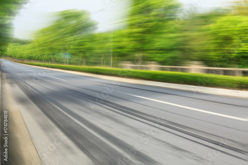 Motion blurred asphalt road and green forest