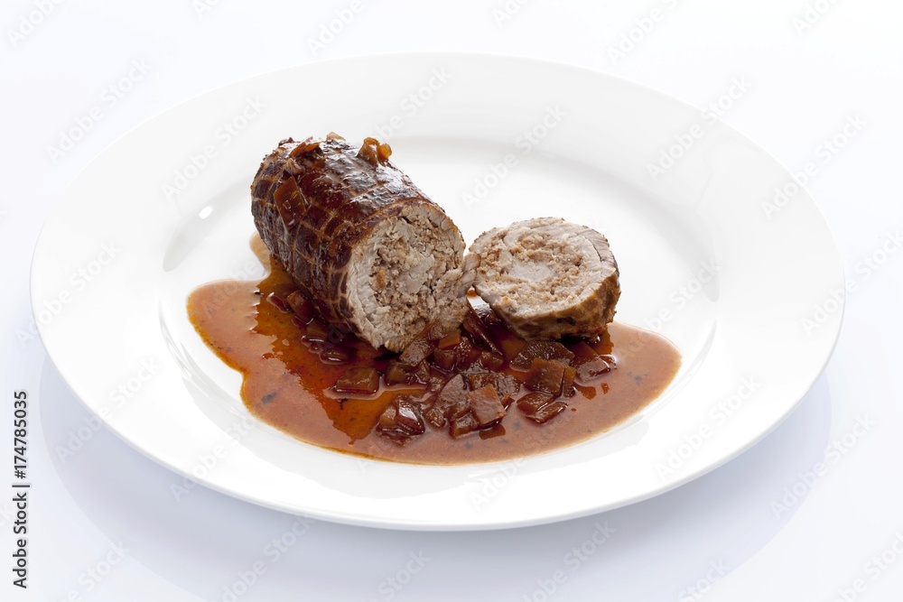 Braised pork roulade stuffed with minced meat and onion sauce on a porcelain plate Braised pork roulade stuffed with minced meat and onion sauce on a porcelain plate