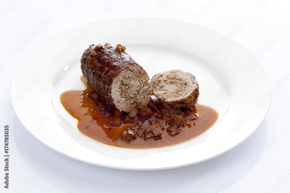 Braised pork roulade stuffed with minced meat and onion sauce on a porcelain plate