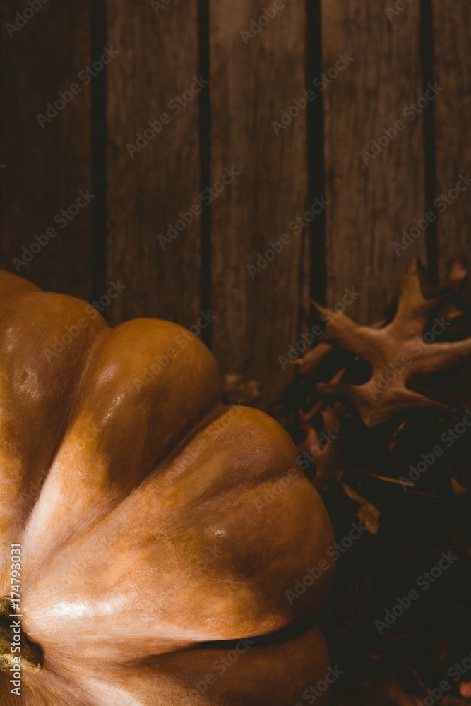 Pumpkin by autumn leaves on wooden table Pumpkin by autumn leaves on wooden table