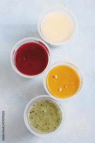 Cups of yoghurt, kiwi, mango, strawberry and natural