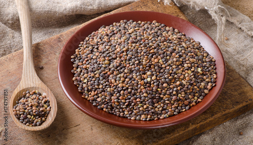 Dry Organic Brown Lentils in bowl on a old wooden board