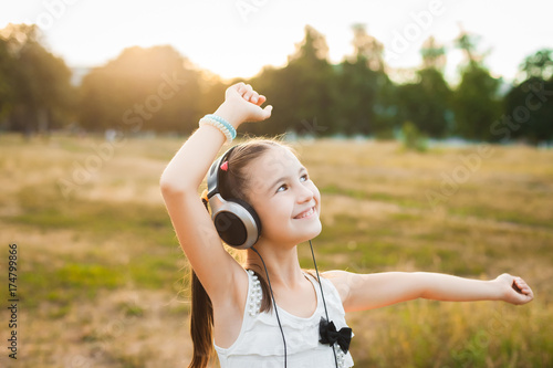 joyful girl listening music and dancing in the field