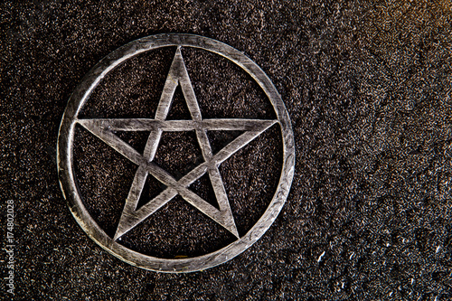 Gray metal pentagram on slate background with water drops photo