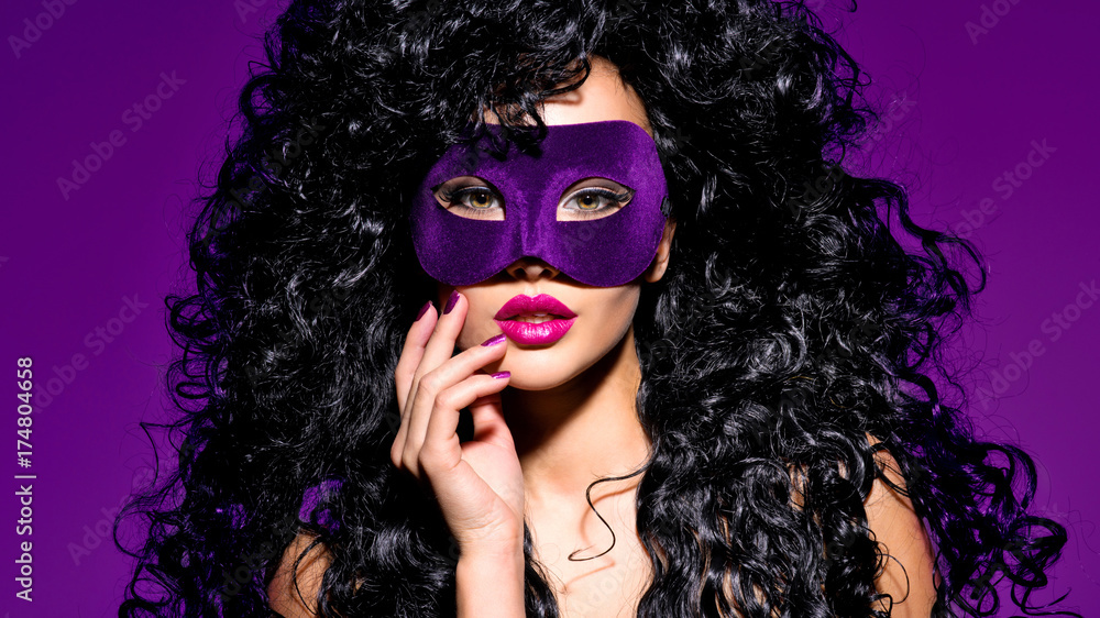 Fototapeta premium Beautiful woman with black hairs and violet theatre mask on face.