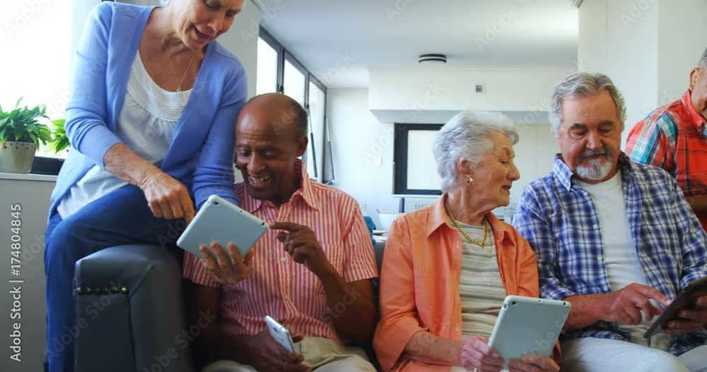 Happy senior friends using digital tablet on sofa Happy senior friends using digital tablet on sofa
