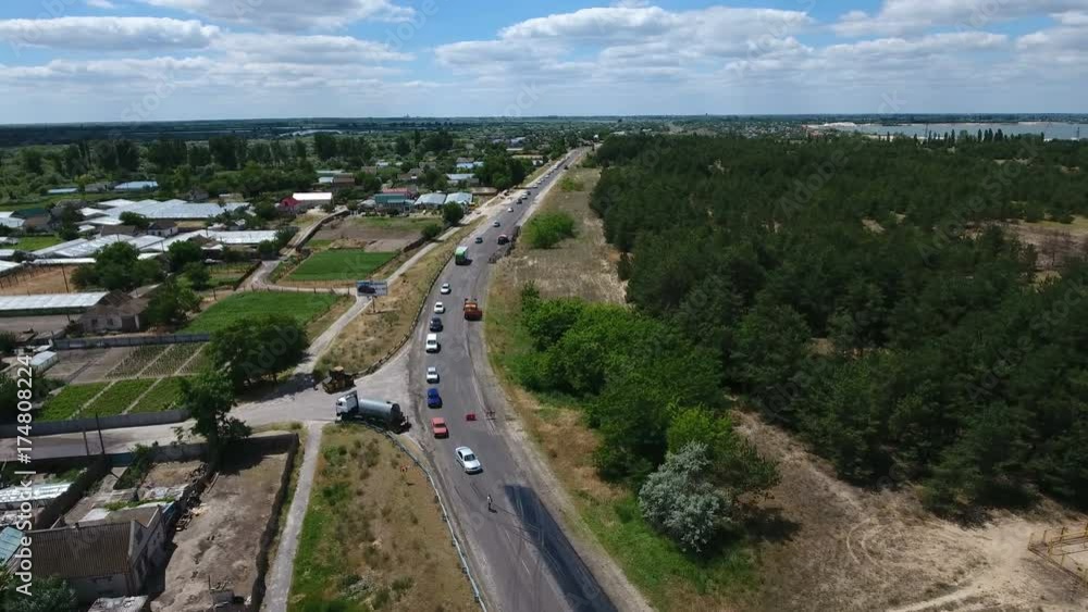 An astonishing bird`s eye view of a road repairing and blacktopping with an excavator breaking old asphalt, trucks and other vehicles standing nearby on a sunny day in summer. An astonishing bird`s eye view of a road repairing and blacktopping with an excavator breaking old asphalt, trucks and other vehicles standing nearby on a sunny day in summer.