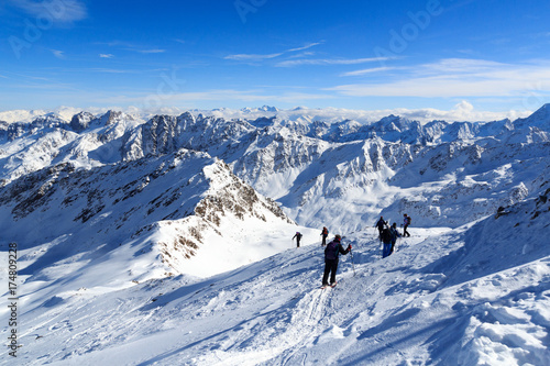 Group of people hiking on snowshoes and mountain snow panorama with blue sky in Stubai Alps, Austria