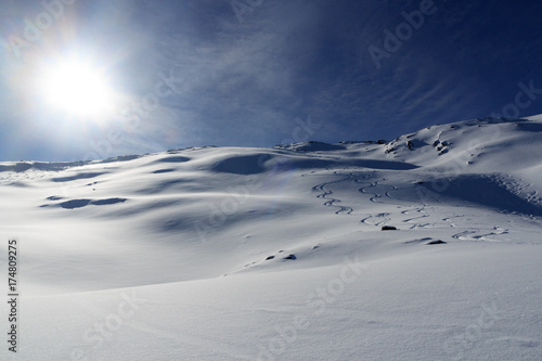 Mountain panorama with snow, ski tracks, sun and summit cross in winter in Stubai Alps, Austria