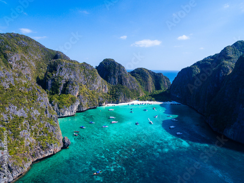 Top Aerial view of tropical island with limestone rocks, white beach and blue clear water. Maya bay with many boats and speedboats above coral reef. Phi-Phi Islands, Krabi, Thailand.