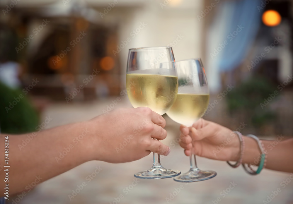 Man and woman holding glasses of white wine on blurred background