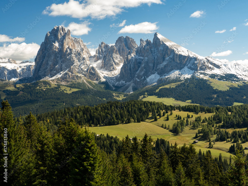 View of beautiful landscape in the Alps with fresh green meadows and snow-capped mountain tops in the background on a sunny day with blue sky and clouds in autumn. September, Dolomites