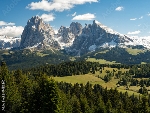 View of beautiful landscape in the Alps with fresh green meadows and snow-capped mountain tops in the background on a sunny day with blue sky and clouds in autumn. September, Dolomites