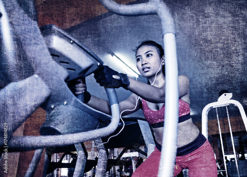 dramatic edit of young sexy sweaty Asian woman training hard at gym using elliptical pedaling machine