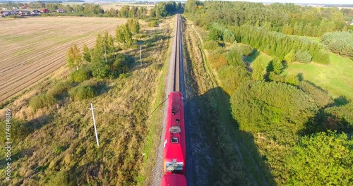 AERIAL railway: Long cargo train transporting wagons across the autumn forest and fields