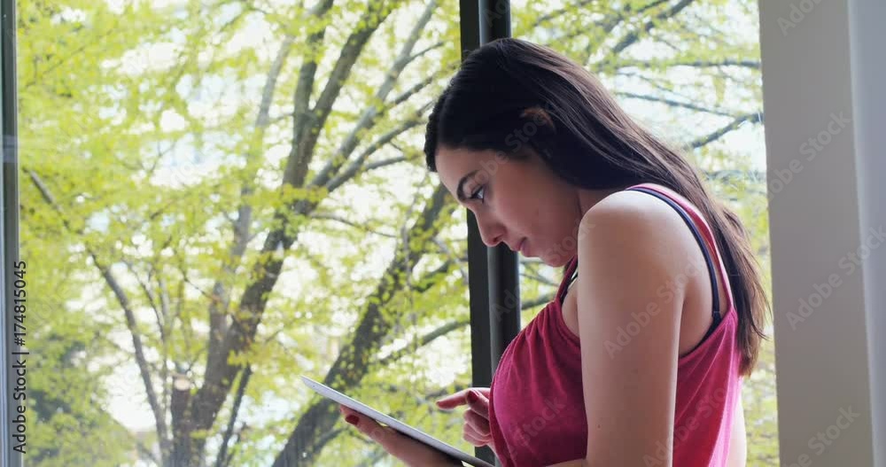 Beautiful woman using digital tablet near window Beautiful woman using digital tablet near window