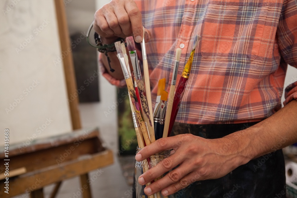 Man selecting a paintbrush - obrazy, fototapety, plakaty 