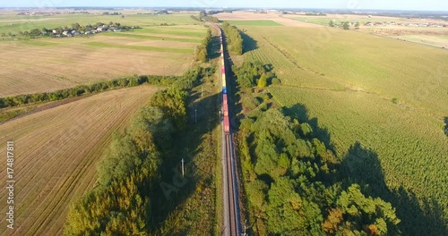 AERIAL railway: Long cargo train transporting wagons across the autumn forest and fields