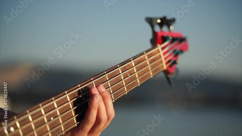 Close-up shot of a man playing bass guitar. View to the hand on fingerboard photo