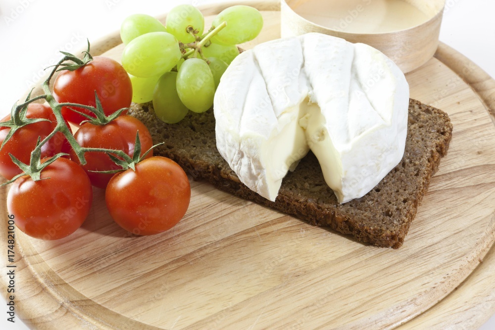 Chardonnay cheese on a board with grapes, tomatoes and bread Chardonnay cheese on a board with grapes, tomatoes and bread