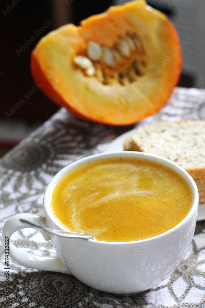 Pumpkin soup in white mug on table. Pumpkin soup in white mug on table.