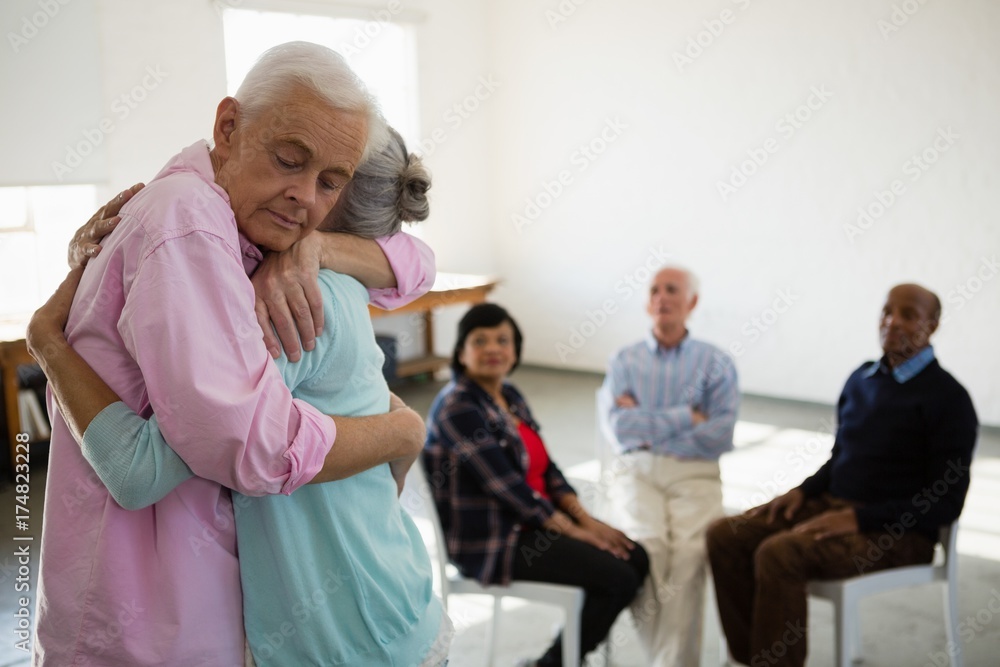 Obraz premium Senior friends looking at man and woman embracing
