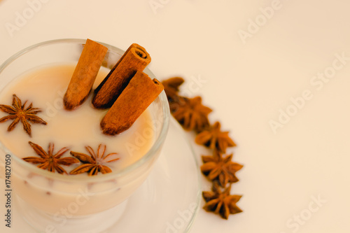 Indian masala tea with spices and milk on white background.