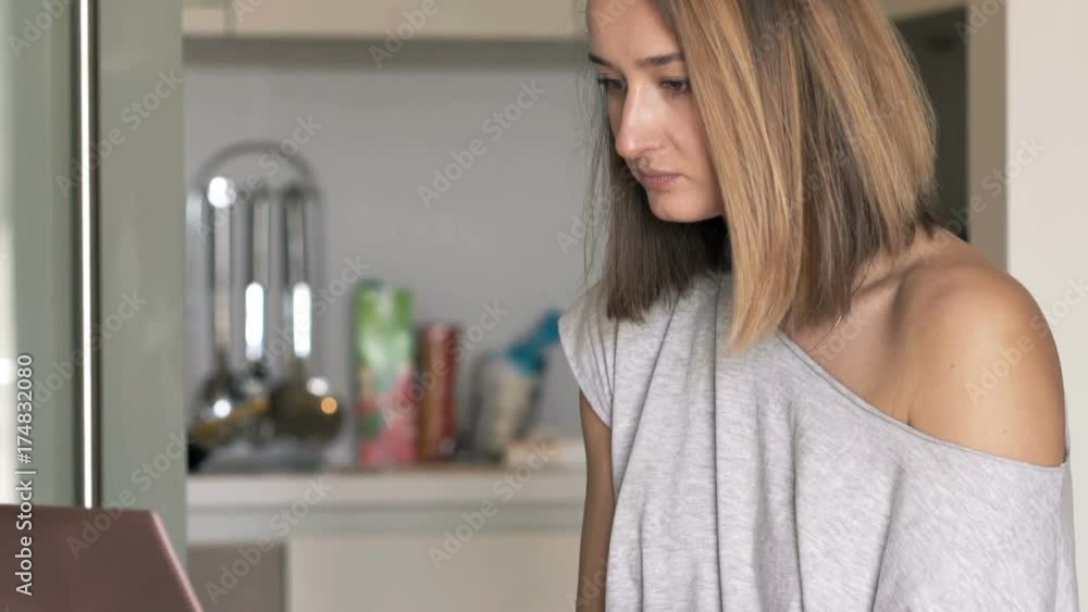 Young woman working on laptop and drinking coffee in kitchen at home
Young woman working on laptop and drinking coffee in kitchen at home