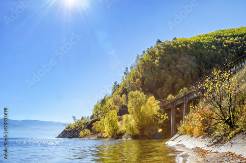 Rays of Sun in the nature with beautiful water, cost and stone bridge close to mountain photo