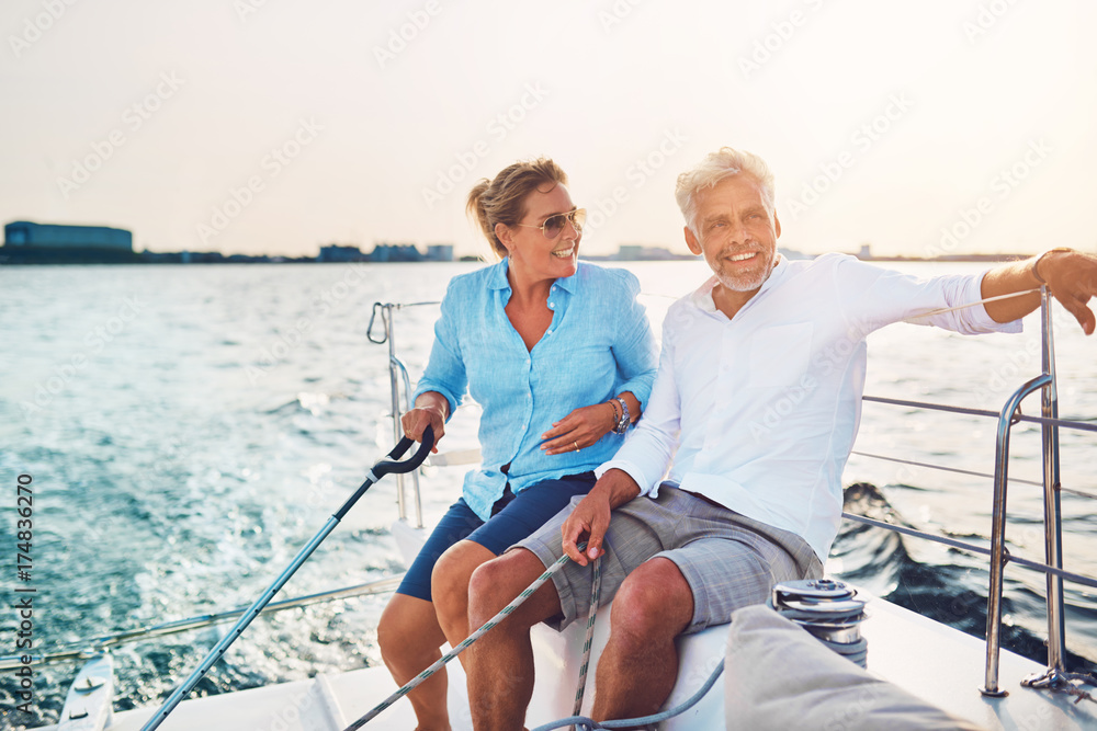 Smiling mature couple enjoying a sunny day sailing together Smiling mature couple enjoying a sunny day sailing together