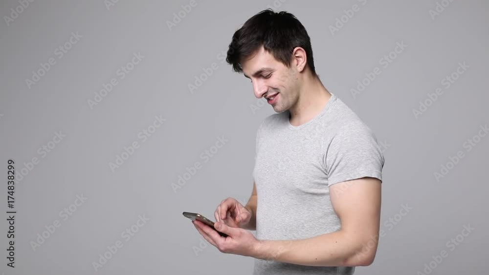 Young man holding phone and scroll screen after typing message inisolated on white. Young man holding phone and scroll screen after typing message inisolated on white.