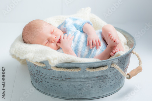 Lovely newborn baby sleeping in little bath