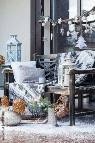 Cozy winter decorations for photo session. Christmas holidays interior. Artificial snow and carpet on the floor. Fir tree decorations, a bench with a gray plaid and a pillow.