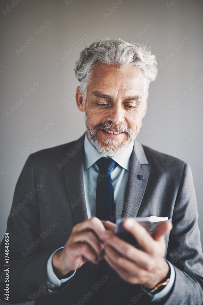 Smiling mature corporate executive reading messages on a cellphone Smiling mature corporate executive reading messages on a cellphone