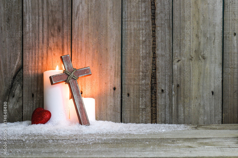 Φωτογραφία White holiday Christmas candles in snow by single red heart and wooden cross wit