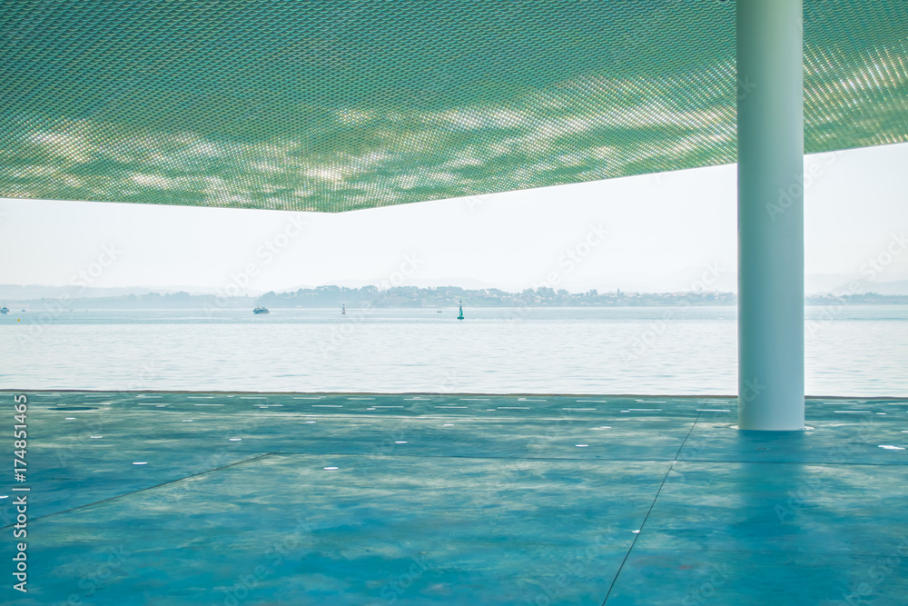 Sea view from a concrete pier covered with a perforated roof.